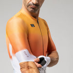 Man wearing orange Gobik cycling jersey with gradient design and zip front