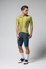 Male cyclist wearing Gobik Magnitude green short sleeve jersey with blue shorts