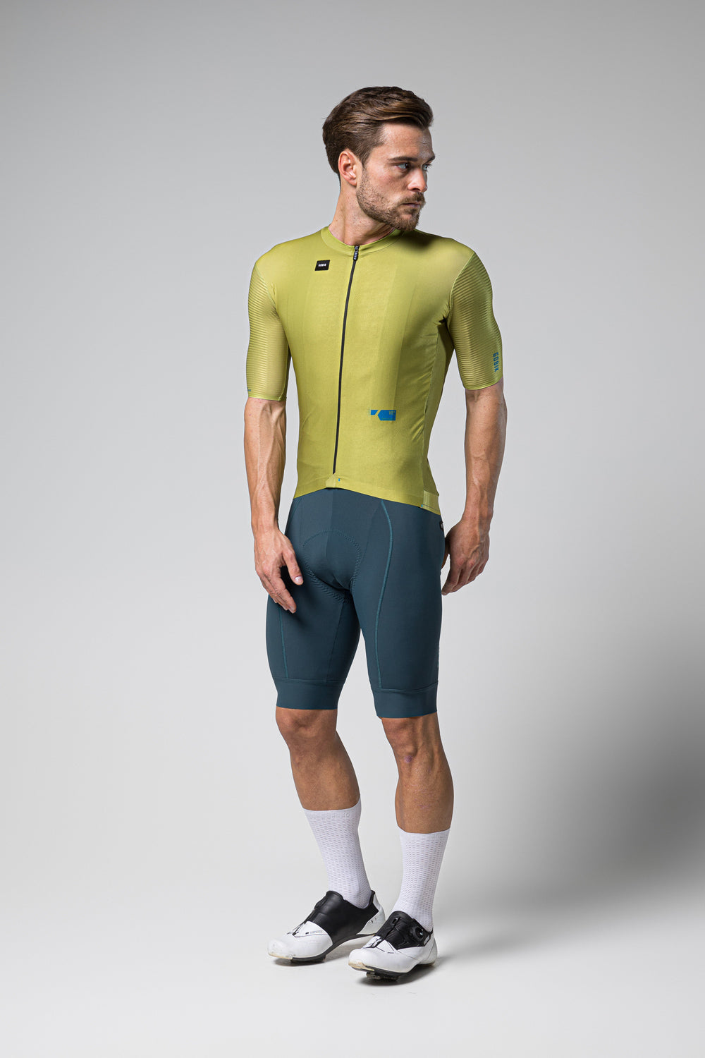 Male cyclist wearing Gobik Magnitude green short sleeve jersey with blue shorts