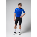 Male cyclist wearing blue Gobik Stark jersey with black shorts in studio setting