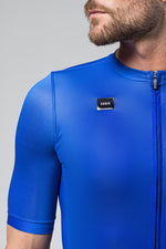 Man wearing bright blue Gobik cycling jersey with zipper and logo