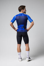 Male cyclist wearing blue Gobik Stark short sleeve jersey, rear view studio shot