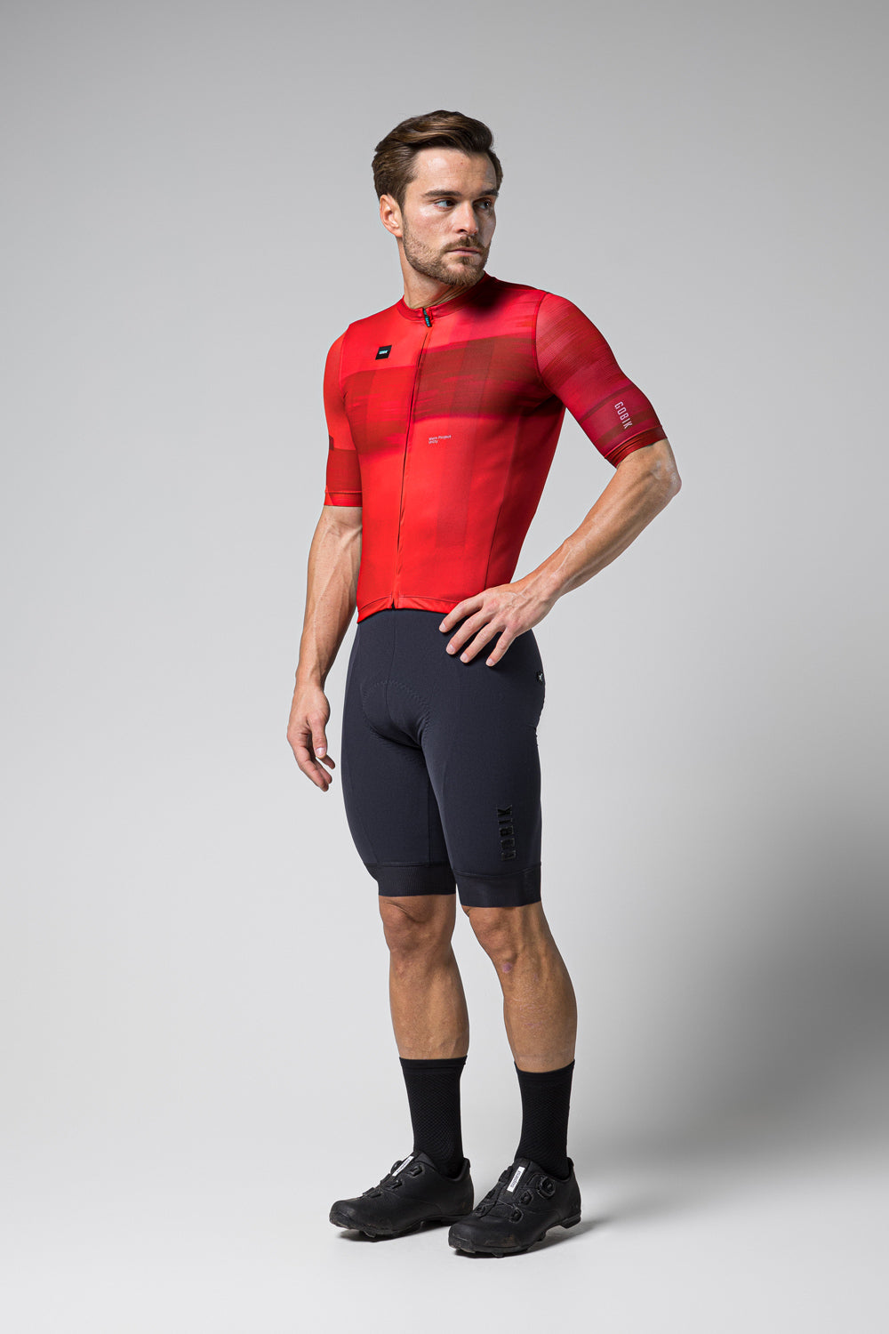Man wearing red Gobik Stark cycling jersey with black shorts in studio