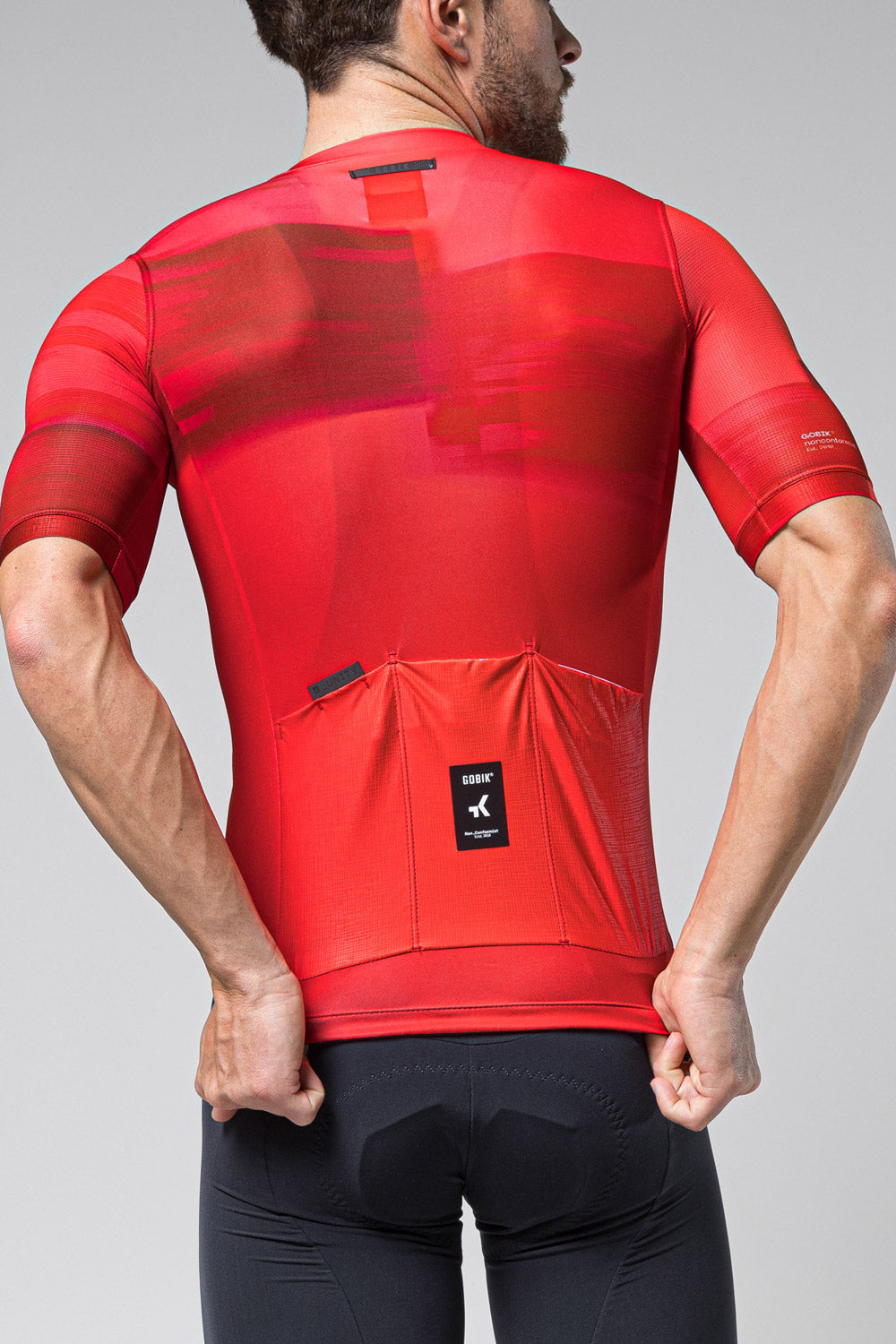 Man wearing red Gobik Stark cycling jersey with geometric pattern, back view