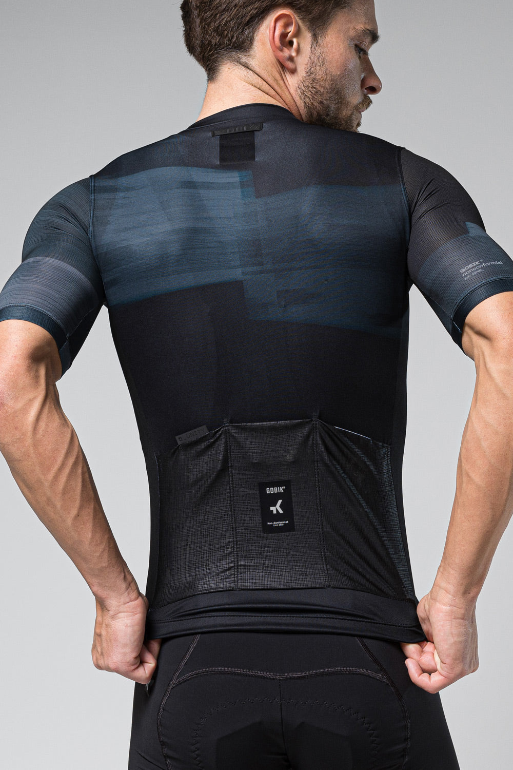 Gobik Stark cycling jersey in dark navy with blue gradient, rear view showing pockets