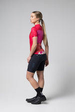 Woman wearing Gobik Stark cycling jersey in azalea pink gradient with black shorts