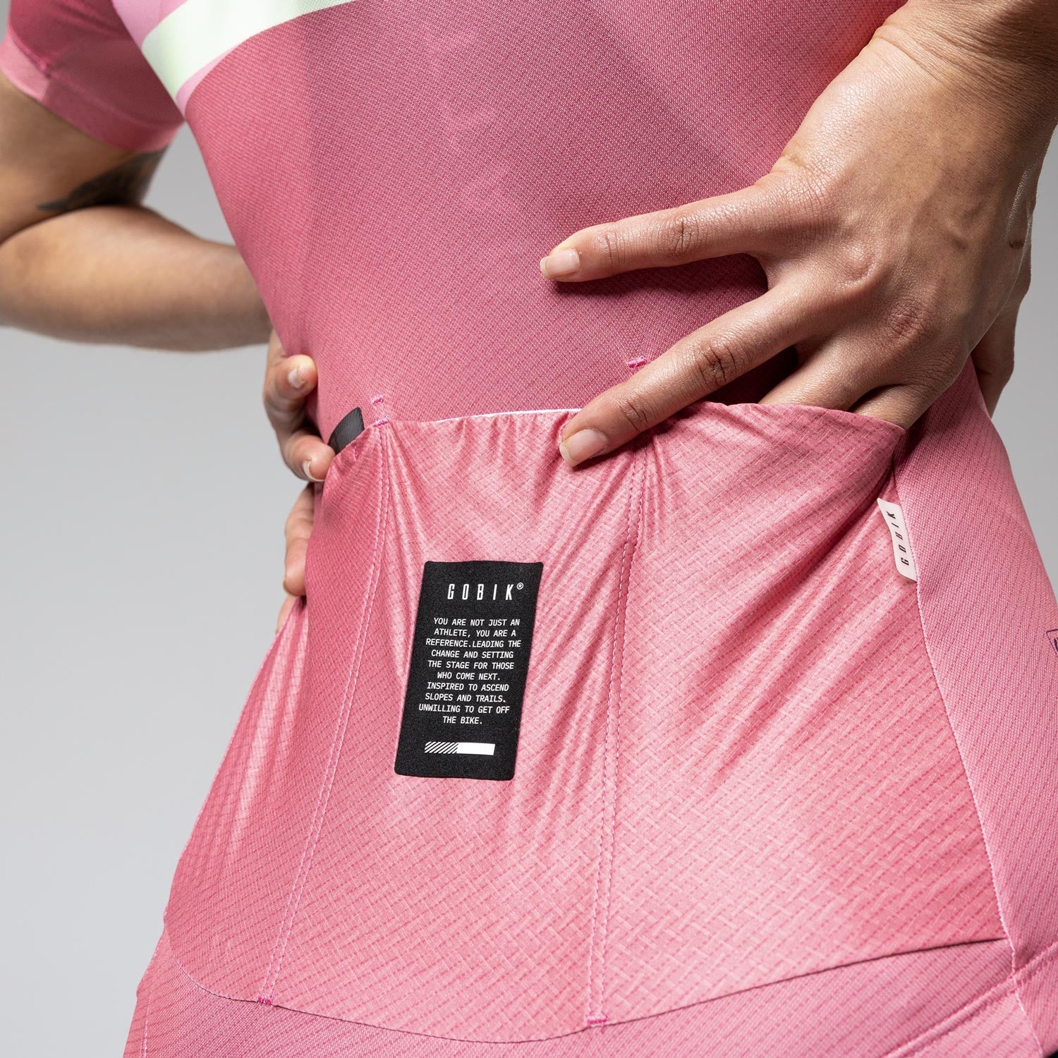 Woman wearing pink Gobik cycling jersey and shorts in studio setting