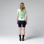 Woman wearing Gobik Stark cycling jersey in seamint green with black shorts, back view