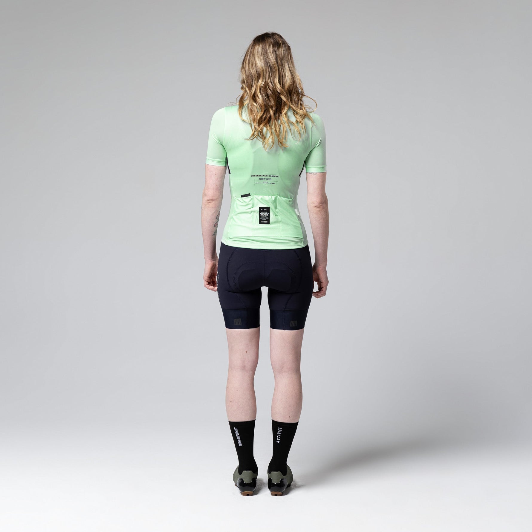 Woman wearing Gobik Stark cycling jersey in seamint green with black shorts, back view
