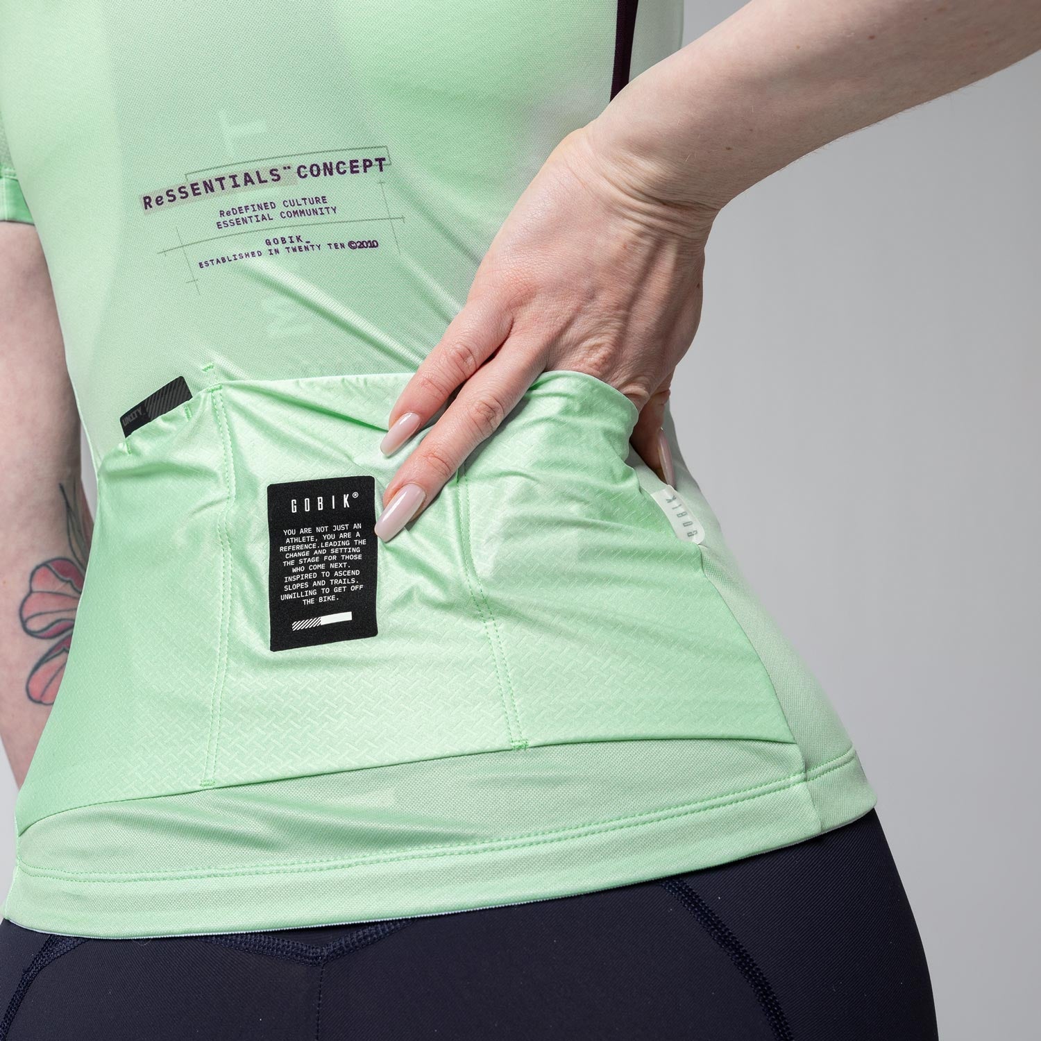 Woman wearing light green Gobik cycling jersey showing back pocket detail