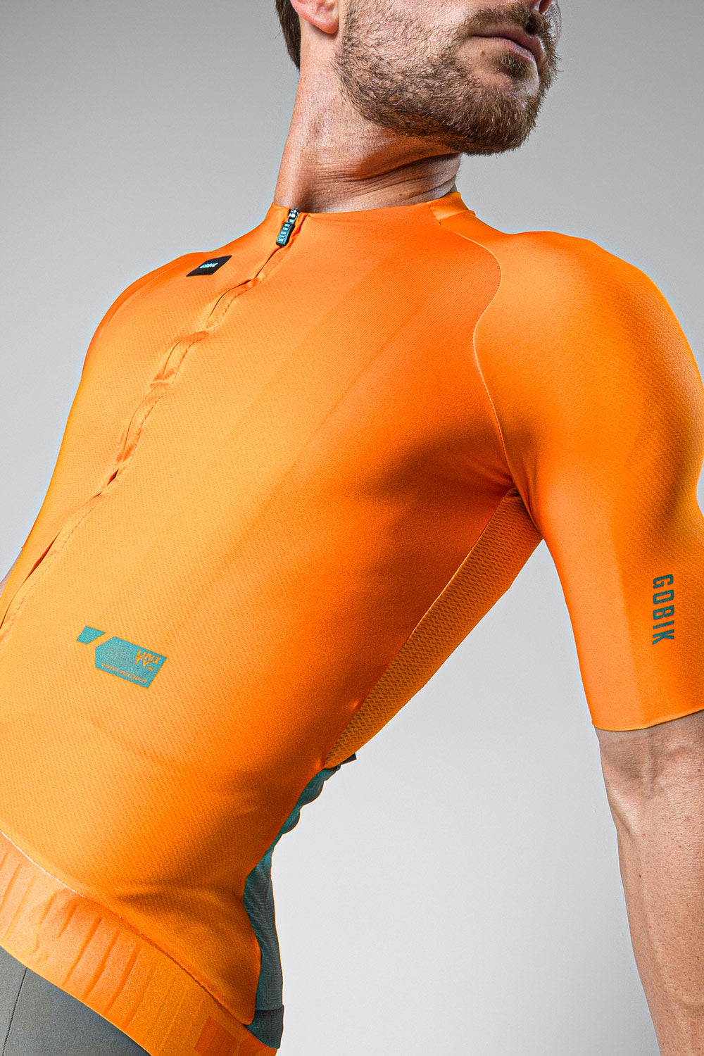 Male cyclist wearing bright orange Gobik CX Pro cycling jersey with short sleeves