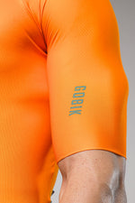Close-up of orange Gobik cycling jersey sleeve showing brand text and technical fabric details