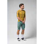 Male model wearing Gobik Infinity cycling jersey in ginger yellow with green shorts
