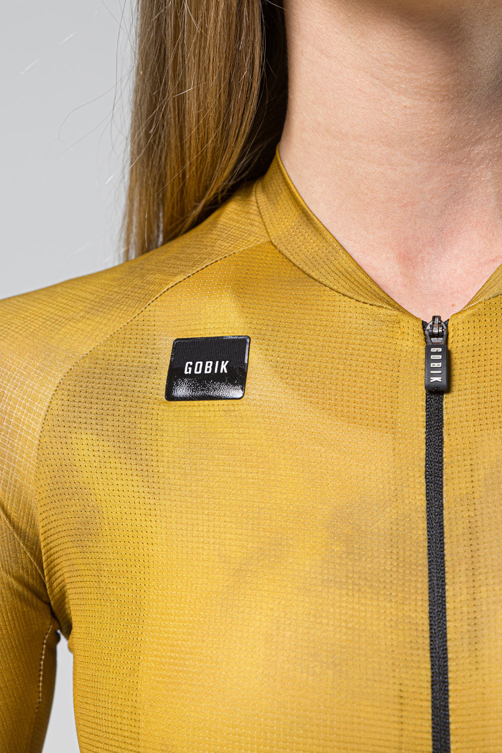 Close-up of GOBIK cycling jersey in golden yellow showing brand label and zipper detail