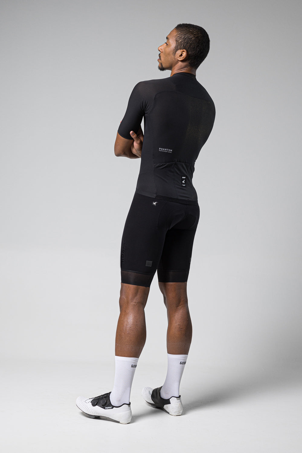 Man wearing black Gobik Phantom cycling jersey and shorts in studio photo