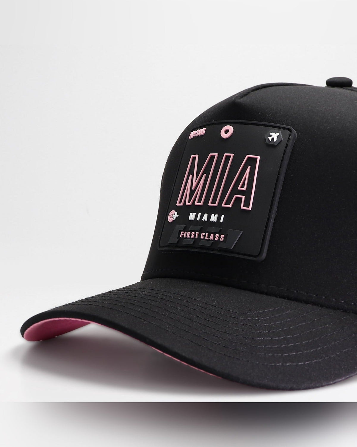 Close-up detail of Wrld Tags Miami MIA rubber patch on black snapback hat with pink lining