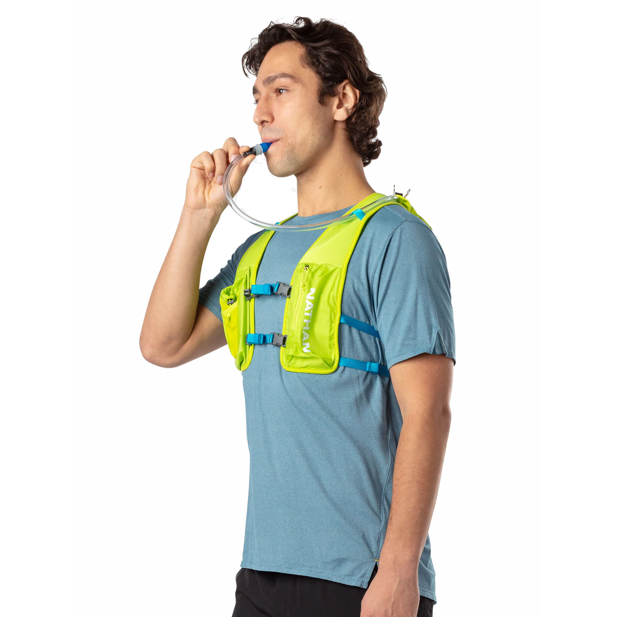 Man wearing Nathan QuickStart hydration vest in lime green, drinking from tube