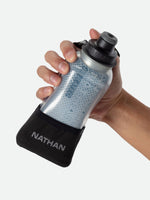 Hand holding Nathan Quick Squeeze handheld water bottle with blue geometric pattern and black wrist strap