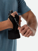 Person holding black Nathan handheld water bottle with hand strap and squeeze cap