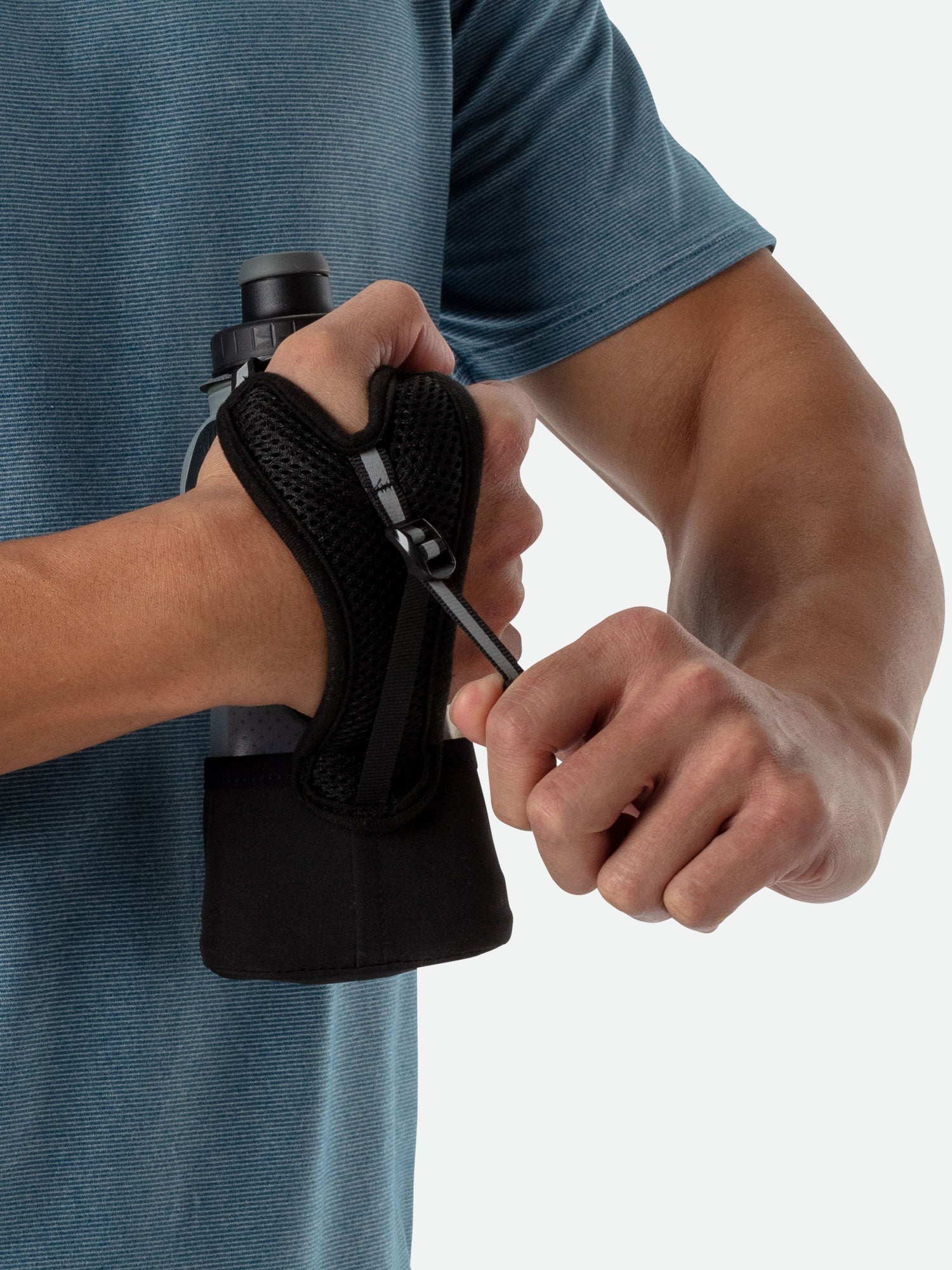 Person holding black Nathan handheld water bottle with hand strap and squeeze cap
