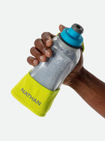 Hand holding Nathan handheld water bottle with blue cap and yellow strap