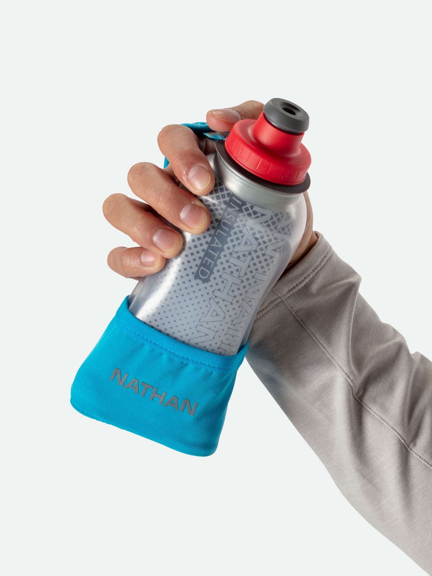 Hand holding Nathan Quick Squeeze handheld water bottle with blue strap against white background