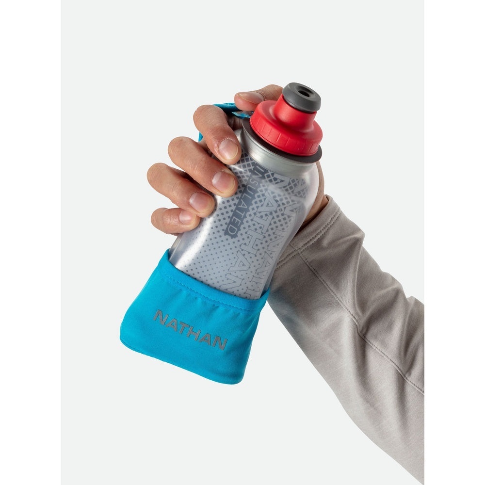 Hand holding Nathan Quick Squeeze handheld water bottle with blue strap and red cap