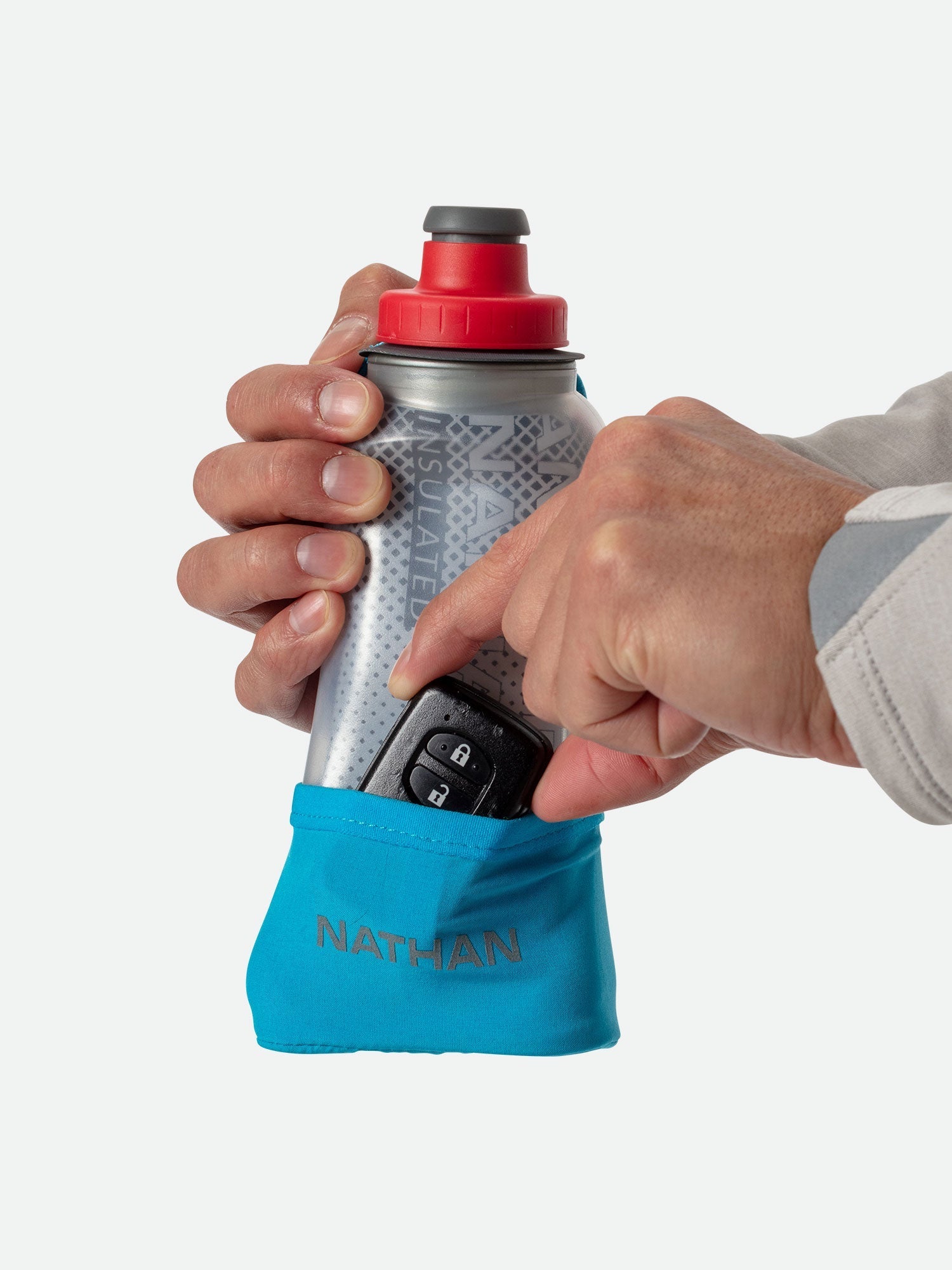 Nathan handheld water bottle with red push-pull cap and blue storage pocket held in hands