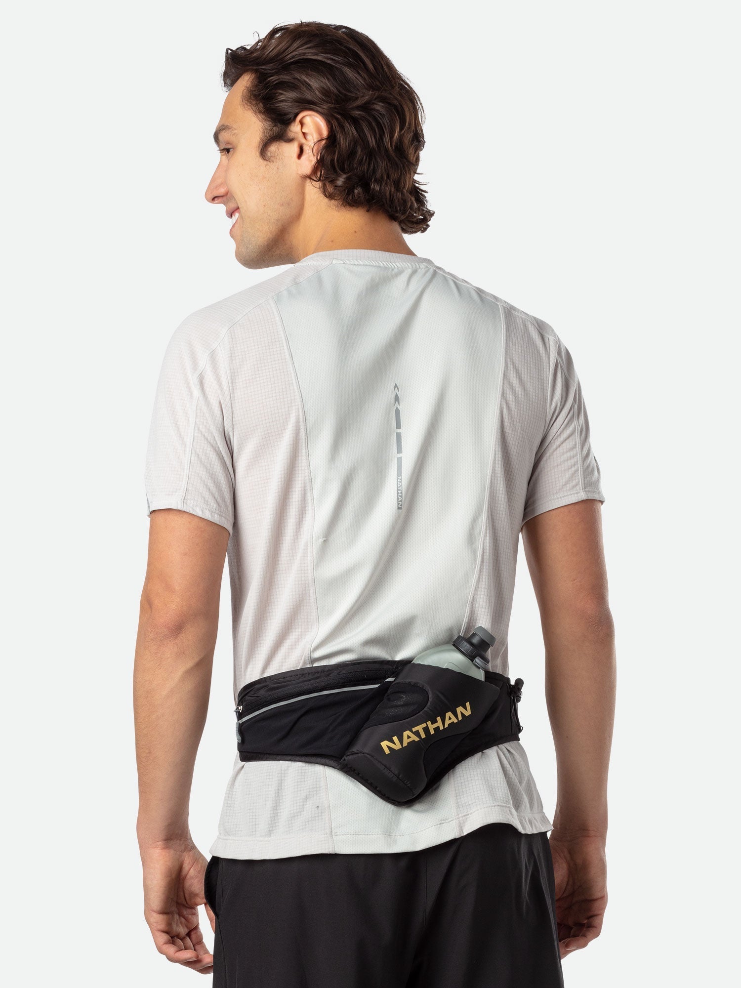 Man wearing Nathan Peak Hydration Waist Pack in black with gold accents during workout