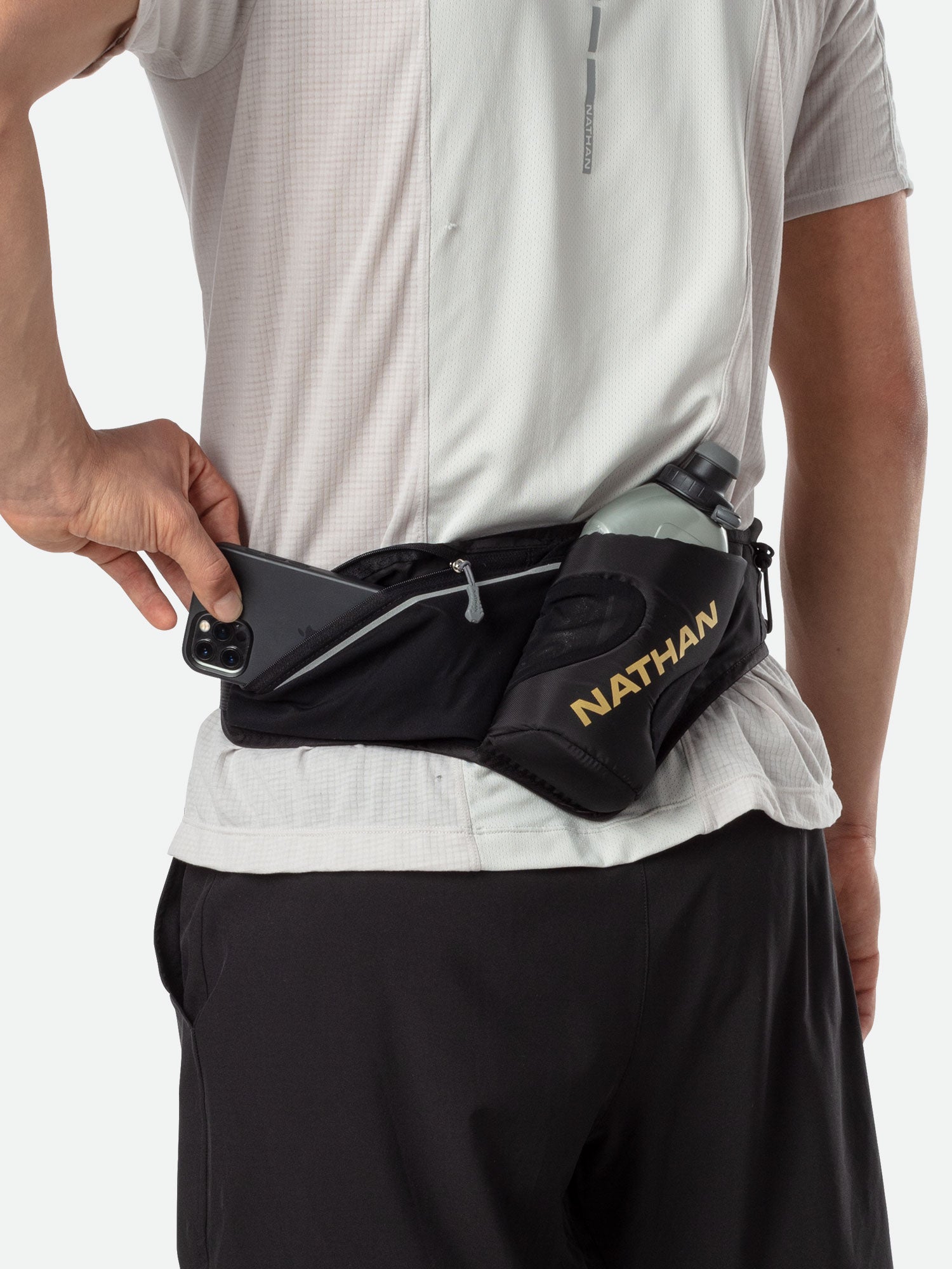 Person wearing Nathan Peak Hydration Waist Pack in black with gold accents around waist