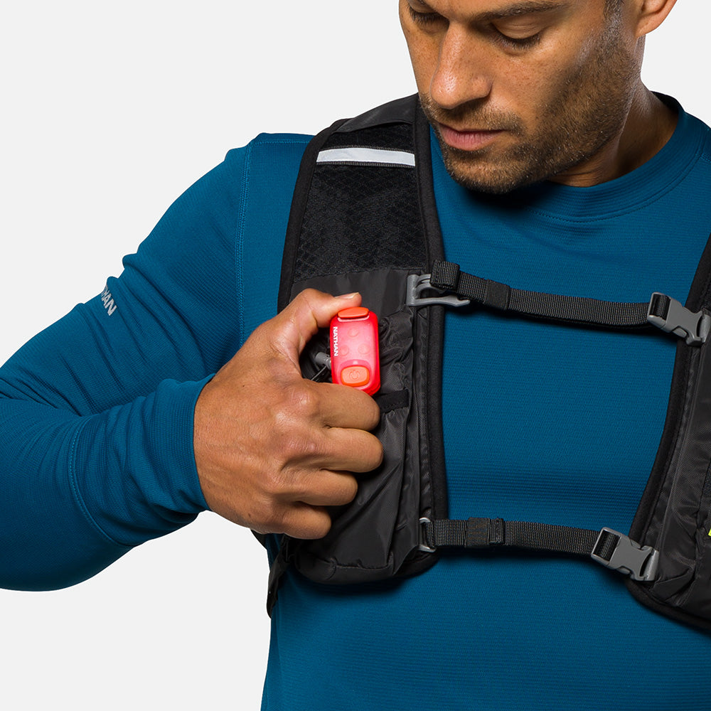 Man wearing vest demonstrating red Nathan LED safety light clip attachment