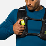 Man wearing backpack demonstrating yellow Nathan LED safety light clip on chest strap