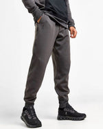 Man wearing On brand dark gray sweat pants with matching hoodie and black sneakers