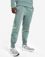 Man wearing On brand sage green sweat pants with matching sneakers on white background