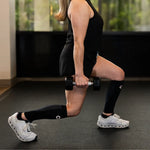 Woman wearing black OS1st CS6 performance calf sleeves while exercising with dumbbells