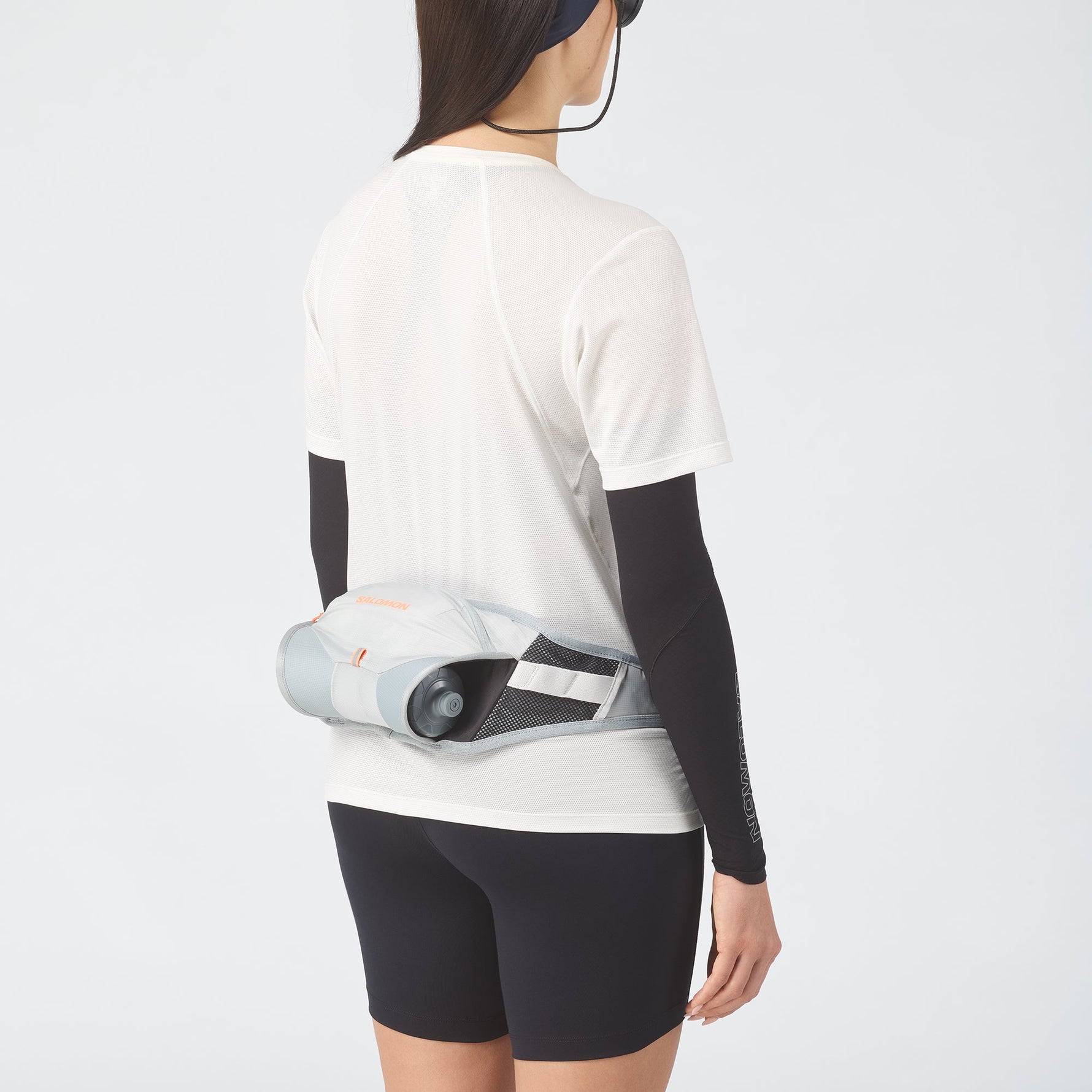 Woman wearing white Salomon running belt with water bottle around waist