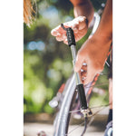 Person using Lezyne Pressure Drive S black mini pump to inflate bicycle tire outdoors