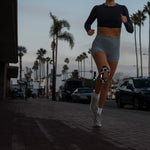 Woman jogging at dusk wearing RockTape GO Reflective knee tape with checkered pattern