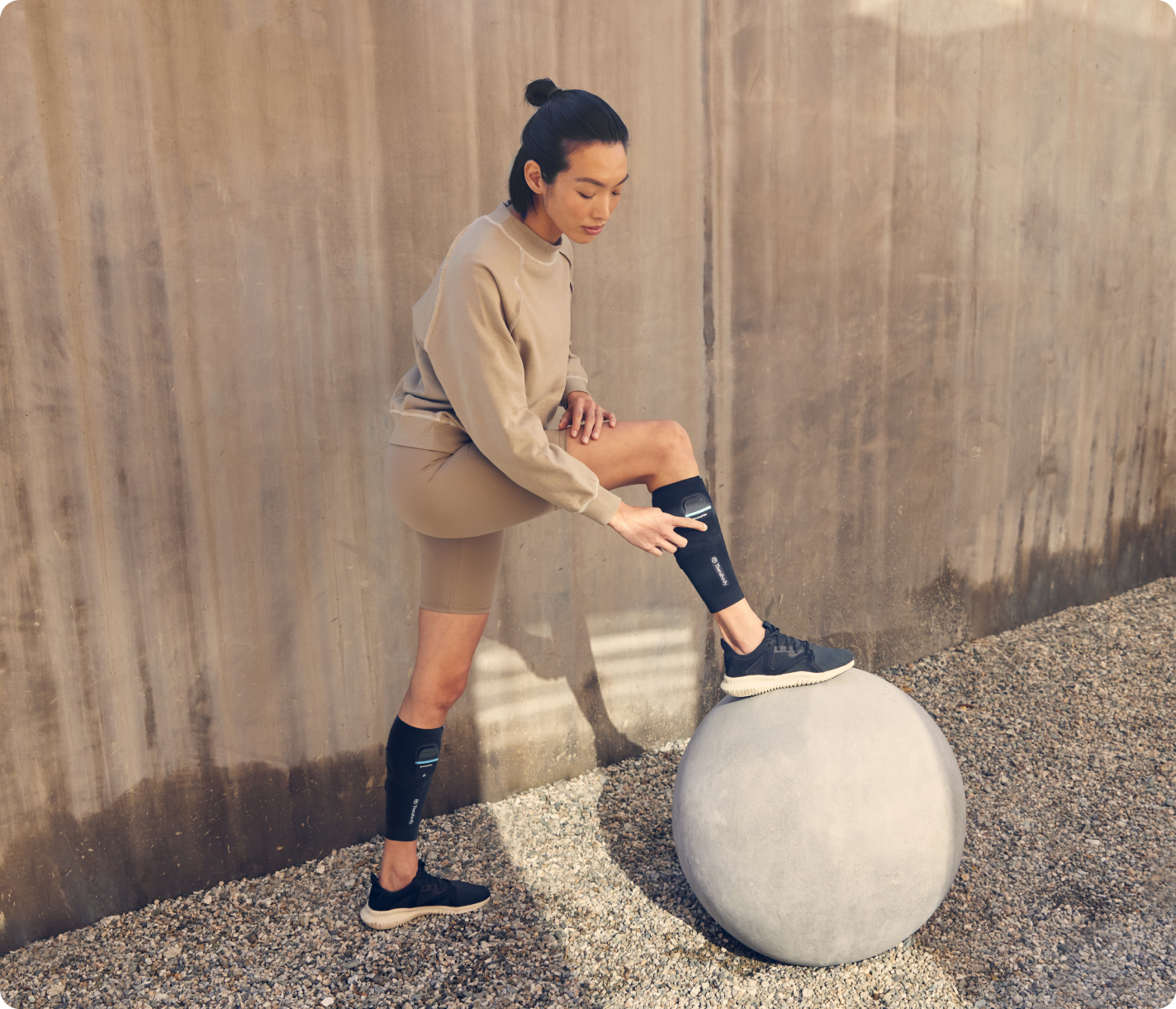 Woman wearing black Therabody RecoveryPulse calf compression sleeves during outdoor workout