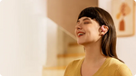 Woman wearing pink Shokz OpenFit Air earbuds with eyes closed, smiling peacefully