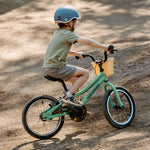 Child riding a mint green Retrospec Koda 16-inch kids bike with helmet outdoors