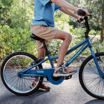 Child riding blue Retrospec Koda kids bike outdoors on pavement