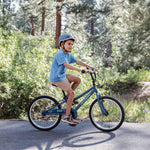 Child riding Retrospec Koda kids bike in overcast blue on outdoor path