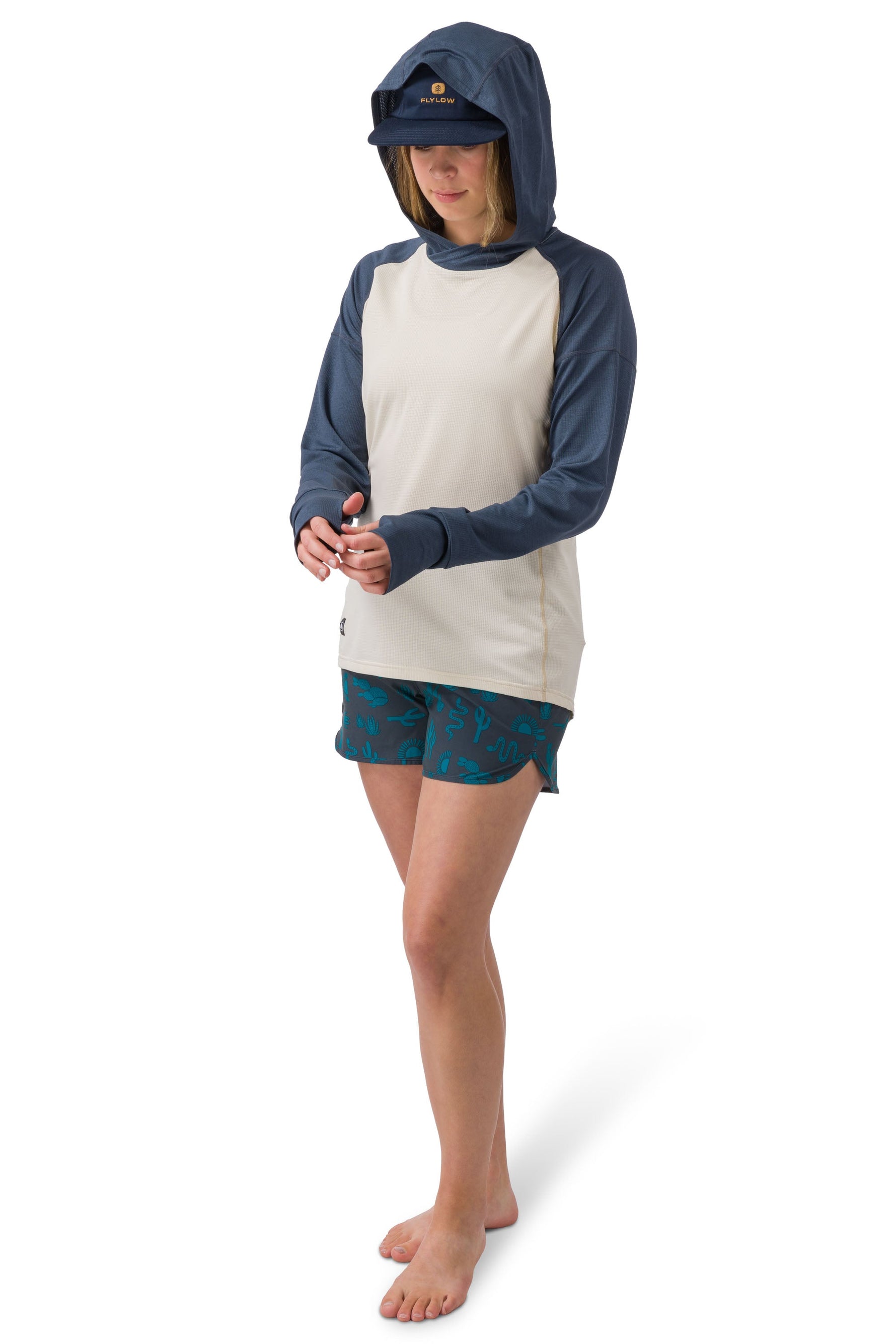 Woman wearing Flylow Gear Moonlight hooded shirt in cloud colorway with navy sleeves