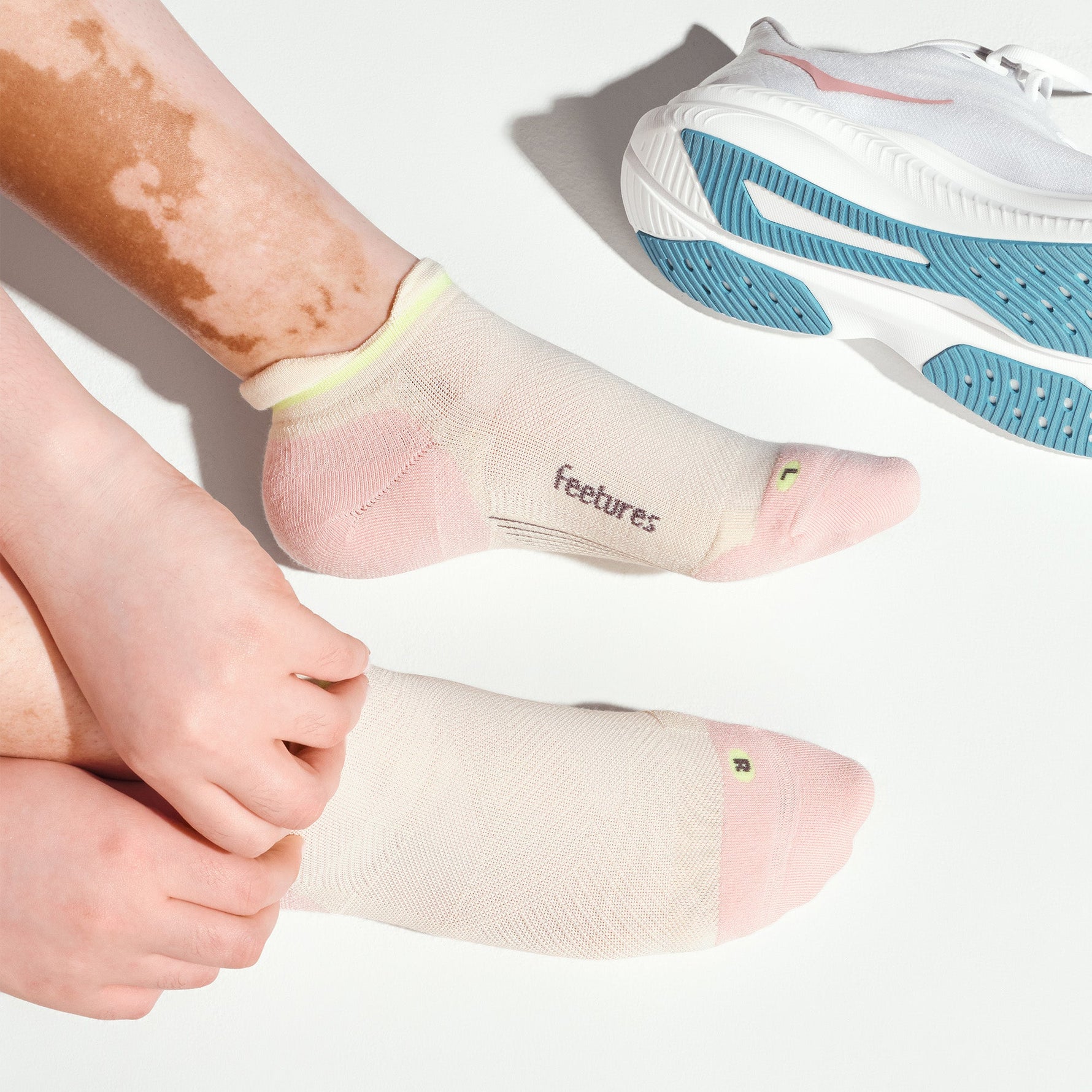 Feetures Elite Max Cushion Tab socks in Stone Ivy worn on feet beside white running shoe