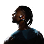 Profile view of athlete wearing white and blue Shokz bone conduction headphones