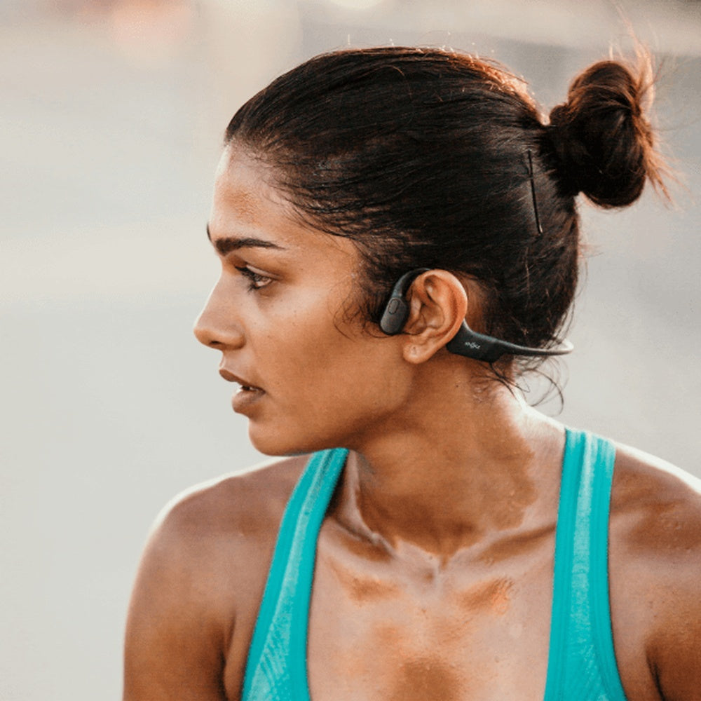 Woman wearing black bone conduction headphones during outdoor workout