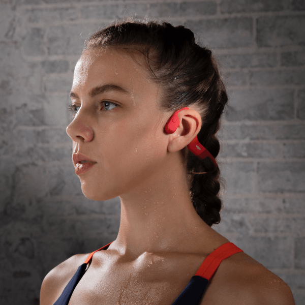 Woman wearing red AfterShokz OpenRun bone conduction headphones during workout