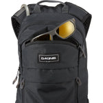 Dakine Syncline 12L black backpack with sunglasses in front pocket on white background