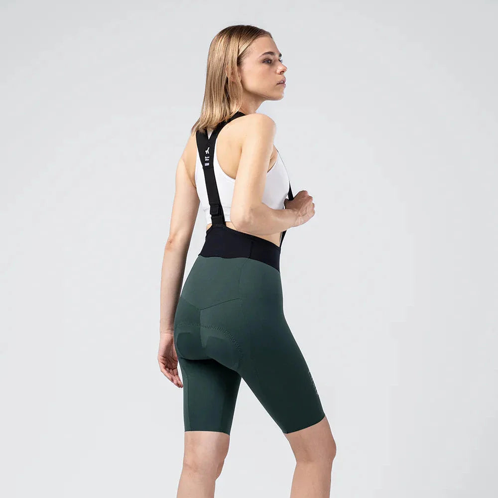 Woman wearing Gobik X Bib Short in dark green cycling shorts with suspenders